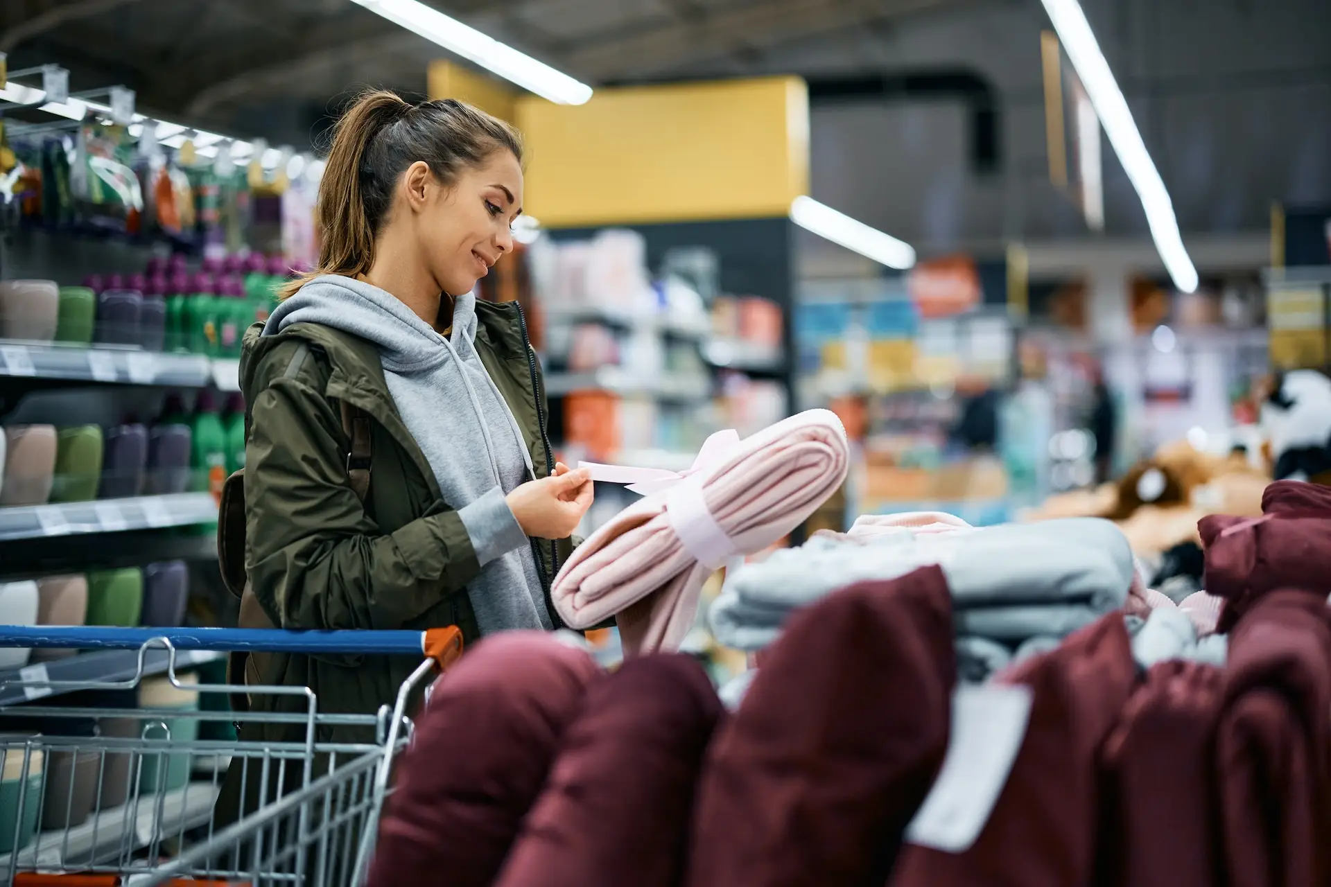 Young happy woman buying blanket in the store.