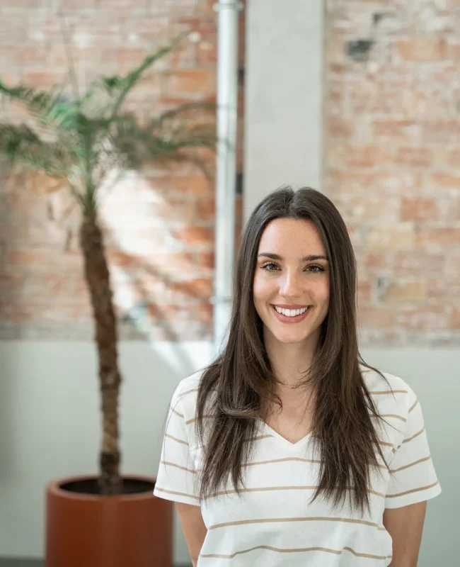 Portrait of young woman employee in a modern office with brick walls doing internship